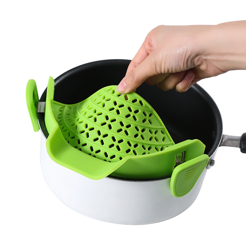 Hand attaching a green silicone strainer to the edge of a pot