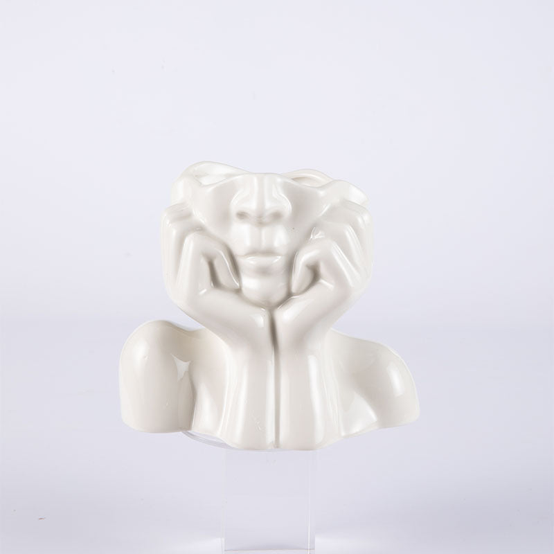 White ceramic face vase with hands resting on the cheeks