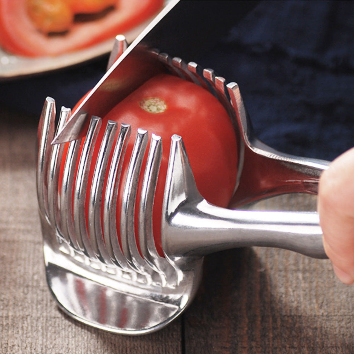 Knife slicing a tomato held in the silver slicing guide