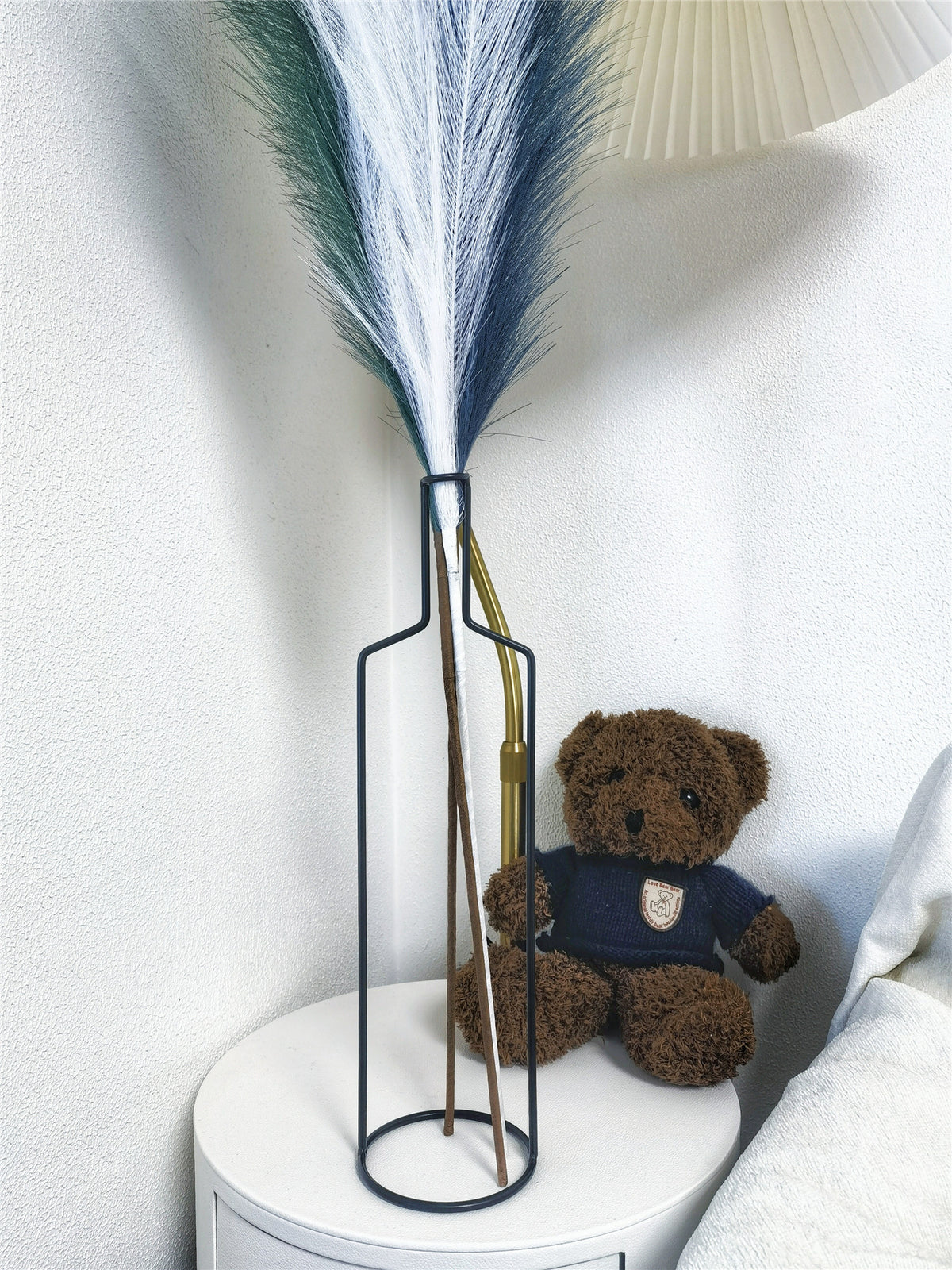 Black wire bottle vase with faux pampas on a bedside table next to a teddy bear