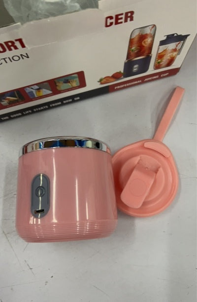Pink portable blender base and travel lid in front of its box