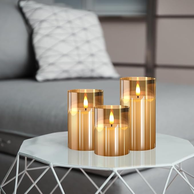 Three gold glass flameless candles on a white side table