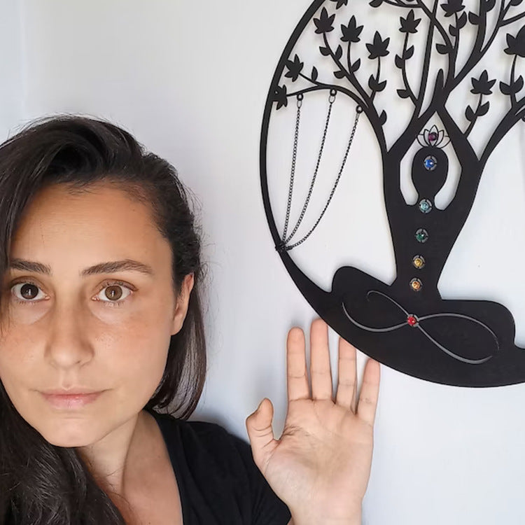 Person holding up a hand beside the round metal meditation wall art to show its scale