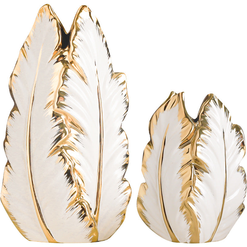 Tall and short white leaf-shaped ceramic vases with gold-plated edges on a white background