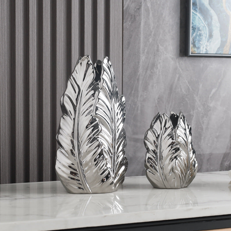 Tall and short bright silver leaf-shaped ceramic vases side by side
