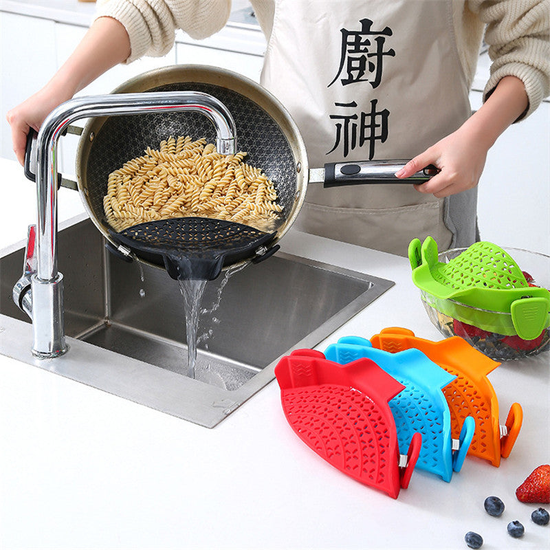 Person draining pasta through a clip-on strainer, with red, blue, orange and green strainers nearby