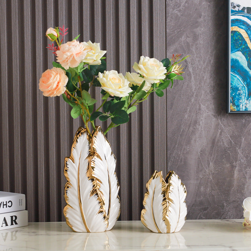 White and gold leaf-shaped ceramic vases holding pink and cream faux roses
