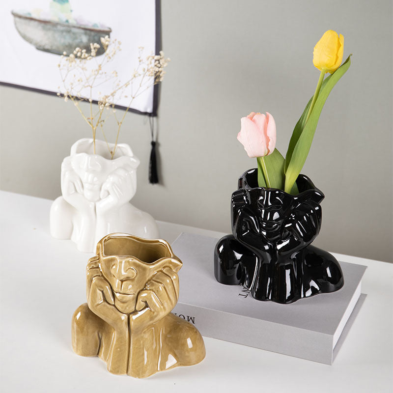 Black, white and mustard yellow ceramic face vases with faux tulips on a table