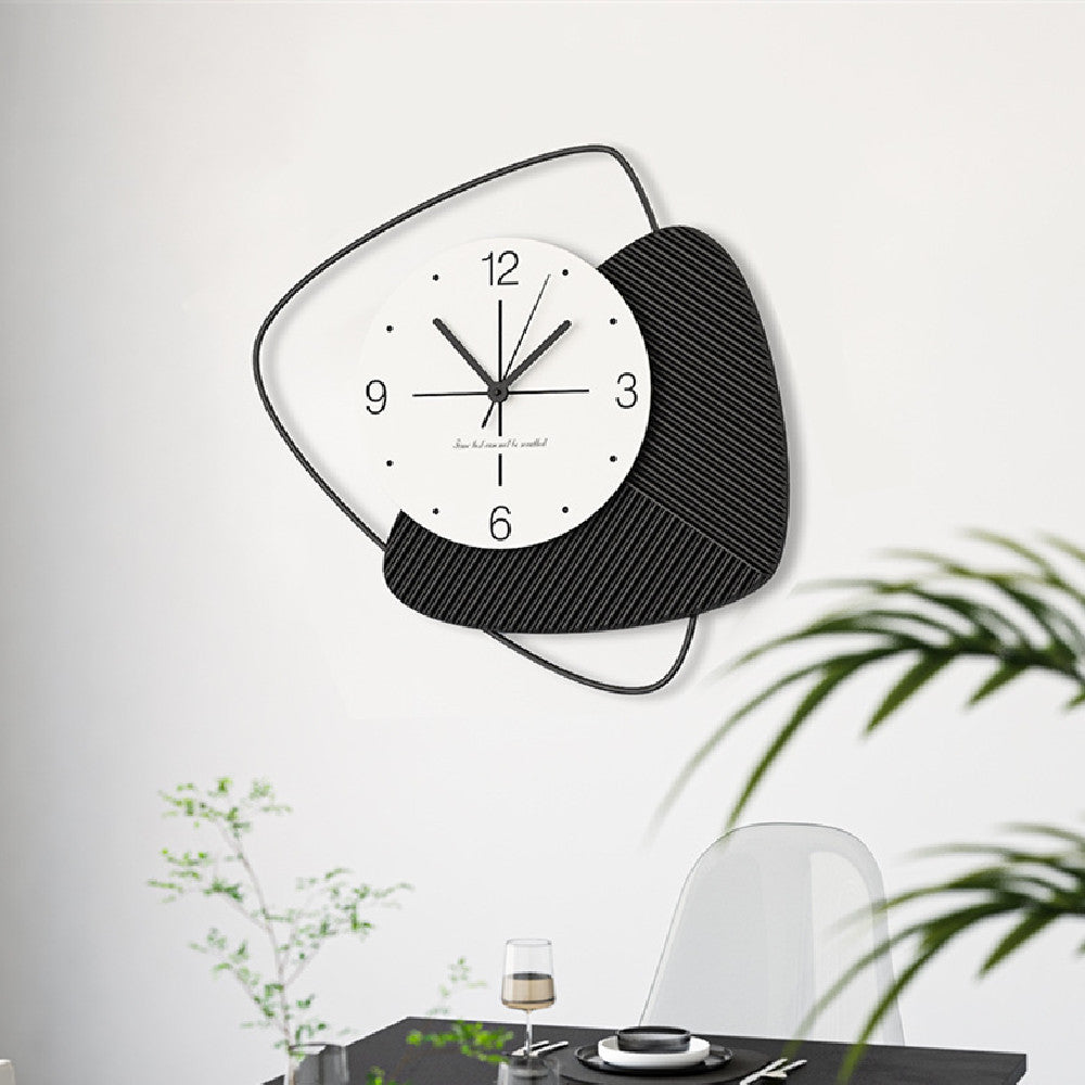 Black and white wall clock on a white wall with plants below