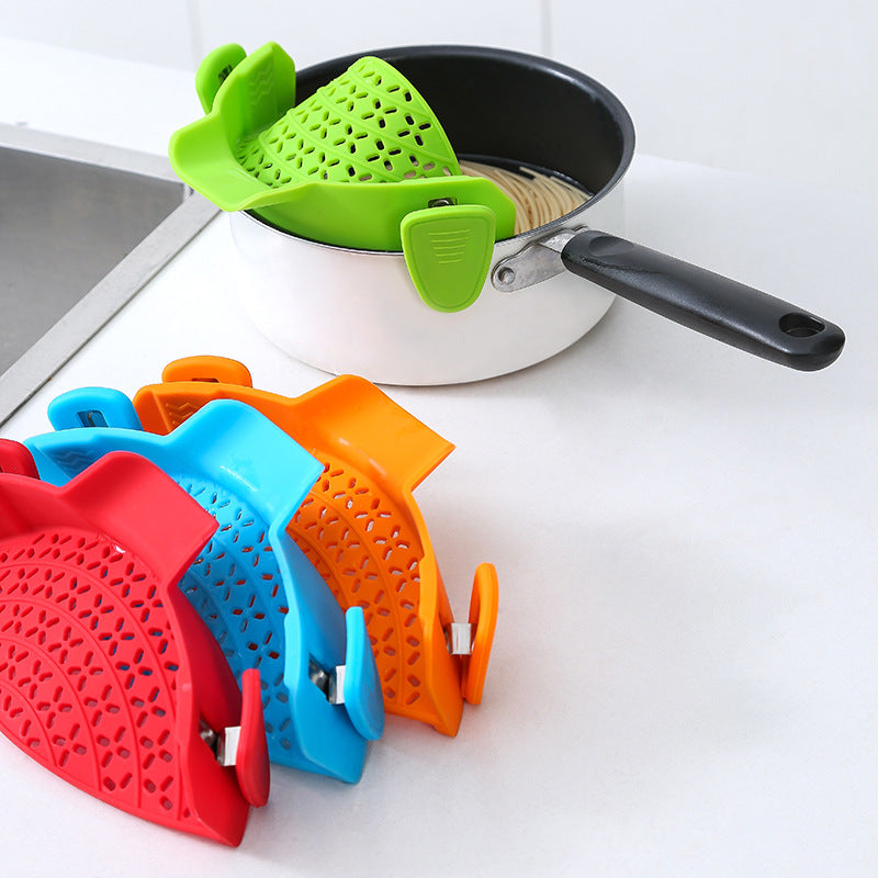 Green strainer clipped to a saucepan, with red, blue and orange strainers stacked in front
